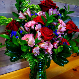 Bouquet of red roses, pink alstroemeria, and carnations in a glass vase