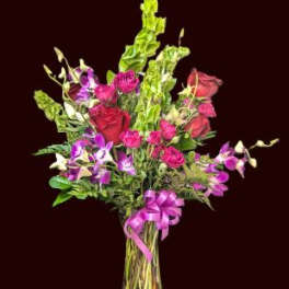 Mixed bouquet of pink and purple flowers in a glass vase with a ribbon