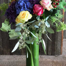 Colorful bouquet of roses and hydrangeas in a tall glass vase