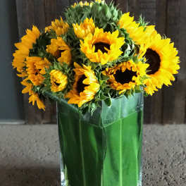 Sunflower bouquet in a tall green glass vase