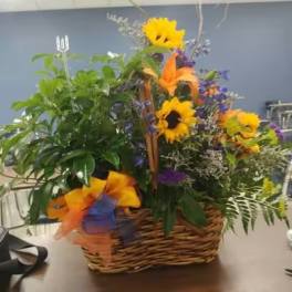 Mixed flower basket with sunflowers, lilies, and purple blooms