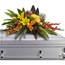 Colorful floral casket spray with yellow, orange, and red blooms