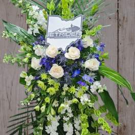 Standing floral spray with white roses, blue flowers, and green accents