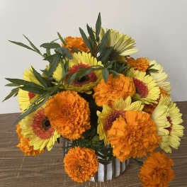 Bouquet of yellow gerbera daisies and orange marigolds in a white vase