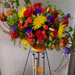 Tall mixed bouquet with red, yellow, purple, and orange flowers on a stand
