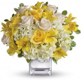 Yellow and white flower bouquet in a clear square vase