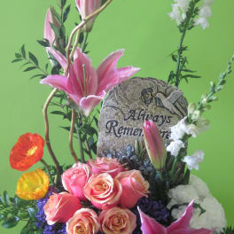 Pink lilies and roses arranged in a pedestal vase with a memorial stone