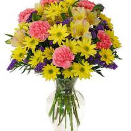 Bouquet of yellow daisies and pink carnations in a clear glass vase