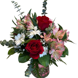 Bouquet of red roses, pink alstroemeria, and white daisies in a glass vase
