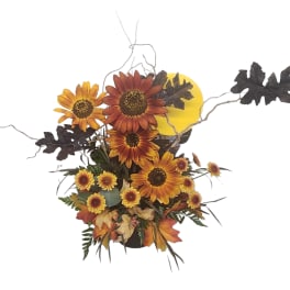 Autumn floral arrangement with sunflowers and fall leaves in a container
