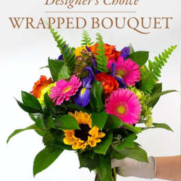 Wrapped bouquet of mixed bright flowers held in a gloved hand