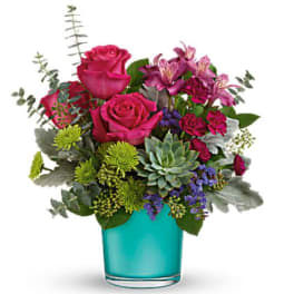 Pink roses and purple flowers in a turquoise glass vase