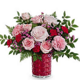 Pink and red roses with carnations in a red glass vase