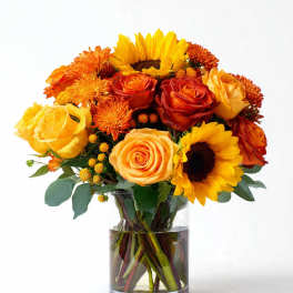 Bouquet of sunflowers, roses, and orange mums in a glass vase