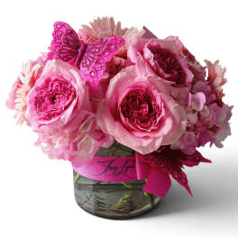 Pink roses and hydrangeas in a glass vase with a butterfly decoration