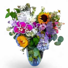 Mixed bouquet with orchids, sunflowers, hydrangeas, and a glass vase