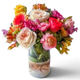 Mixed bouquet of colorful roses and gerbera daisies in a glass vase