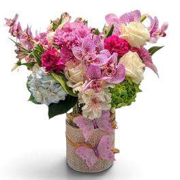 Pink and white mixed bouquet in a burlap-wrapped vase with butterfly decorations