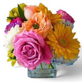 Colorful mixed bouquet of roses and daisies in a square glass vase