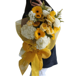Handheld bouquet of yellow and white flowers wrapped in gold mesh