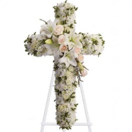 White floral cross arrangement with lilies and roses on a stand