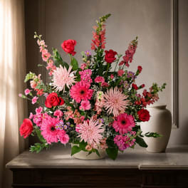 Pink and red mixed flower arrangement in a white vase
