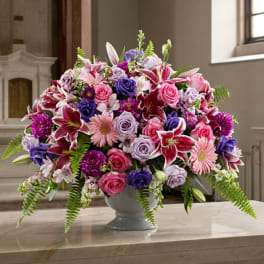 Large mixed bouquet of pink, purple, and white flowers in a gray vase