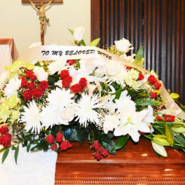 Large red and white funeral flower spray on a casket