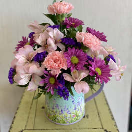 Pink and purple mixed flowers arranged in a decorative metal container