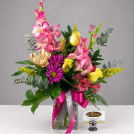 Mixed bouquet with pink gladiolus, yellow roses, and purple daisies in a glass vase