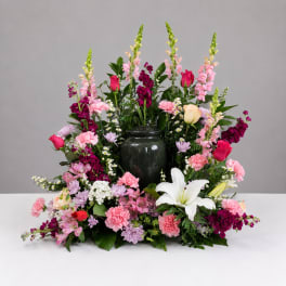 Large floral arrangement with pink, purple, and white blooms in a dark vase