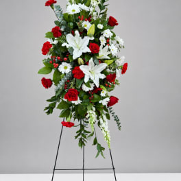 Tall standing floral spray with red roses and white lilies on a black easel