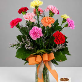 Colorful carnation bouquet in a glass vase with an orange ribbon