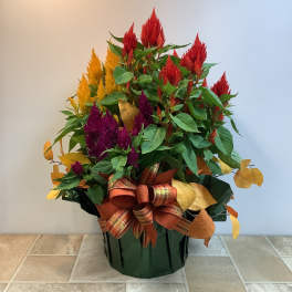 Colorful floral arrangement in a dark green container with a ribbon bow