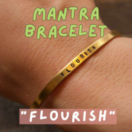 Gold bracelet on a wrist with the word FLOURISH engraved