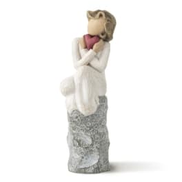 Decorative figurine of a seated woman holding a pink heart