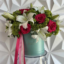 Bouquet of pink roses and white lilies in a teal hat box