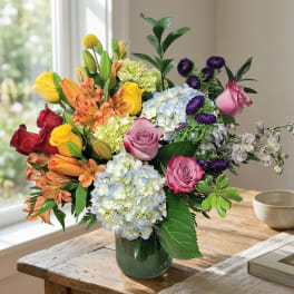 Mixed bouquet of roses, hydrangeas, and alstroemeria in a glass vase