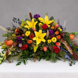 Large colorful floral arrangement with lilies, roses, and ribbons