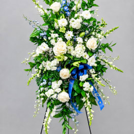 Tall white and blue floral standing spray on a black easel