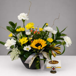 Mixed bouquet with sunflowers, white carnations, and yellow daisies in a black container