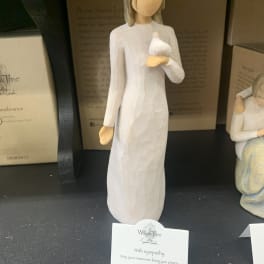 A small angel figurine in a white dress holding a dove