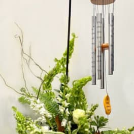 White floral arrangement with a hanging wind chime above it