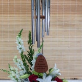 Red roses and white lilies arranged beneath a hanging wind chime