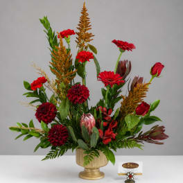 Red floral arrangement in a gold vase with tall mixed blooms