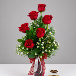 Red roses arranged in a glass vase with small white daisies