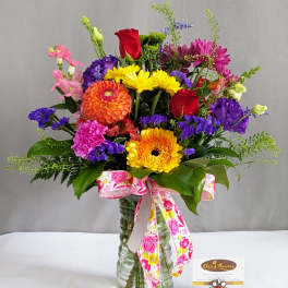 Colorful mixed bouquet in a glass vase with a pink ribbon