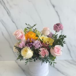 Mixed pastel flower arrangement in a white hat box