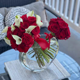 Red rose bouquets with white calla lilies in a glass vase