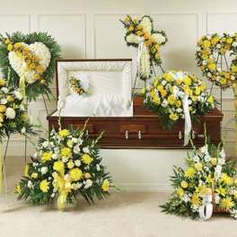 Yellow and white funeral floral tributes arranged around a casket